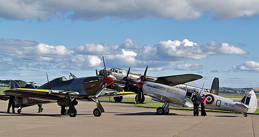 Following their formation and solo displays the Battle of Britain Memorial Flight Spitfire and Hurricane are parked in the foreground while the Lancaster taxies in.