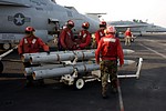 Ordnance crew (red shirts) with AIM-120C AMRAAM, while the Super Hornet is fueled up (purple shirt)