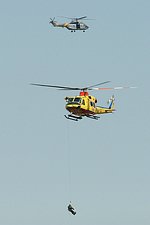 RNLAF AB-412SP performing a winching operation, with the Spanish Puma in the background.